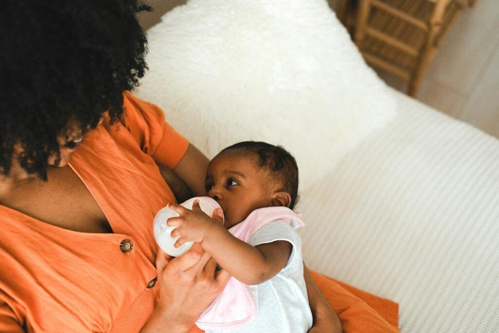 A loving mother feeds her baby with a bottle, encapsulating warmth and care.